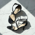 Black high-heeled sandals on a marble surface