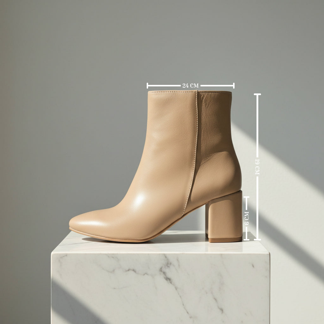 A beige leather ankle boot with a block heel and pointed toe, displayed on a white marble pedestal with dimension lines indicating measurements of 24 cm width, 77 cm height, and 12 cm heel depth against a gray background.