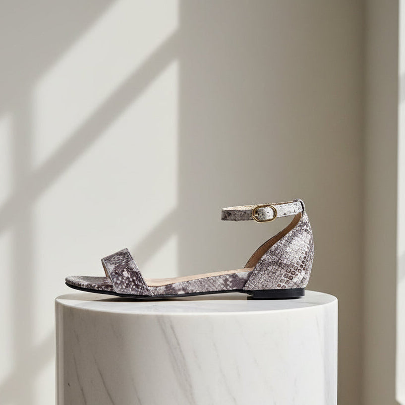Sparkly sandal on a white pedestal with sunlight casting shadows