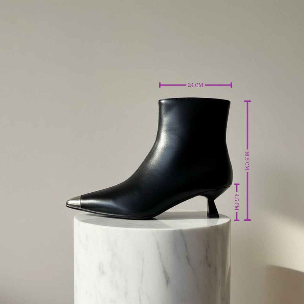 Black ankle boot on a white marble pedestal with measurements indicated.