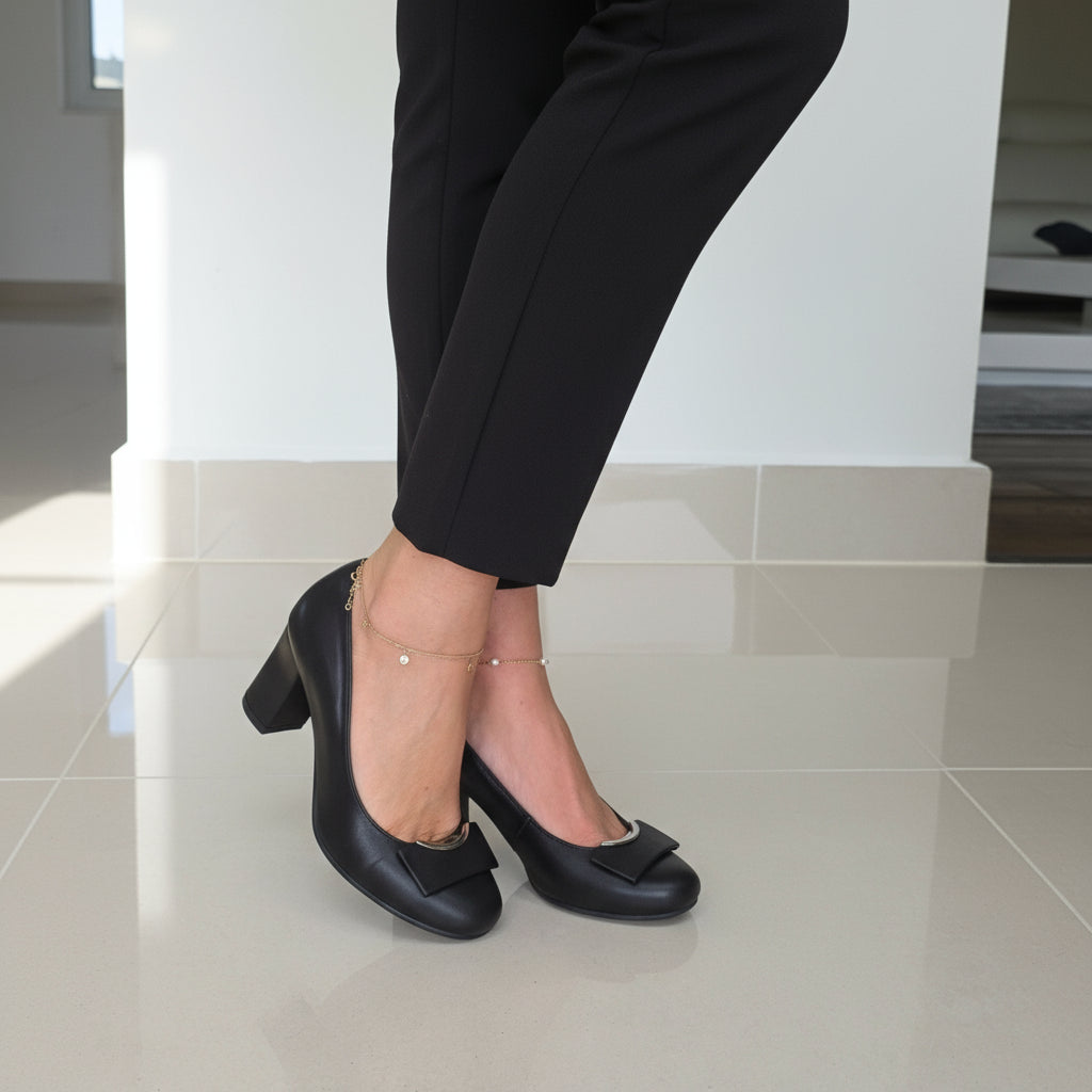 Petite feet wearing GLAM black leather block heel pumps crossed at ankles