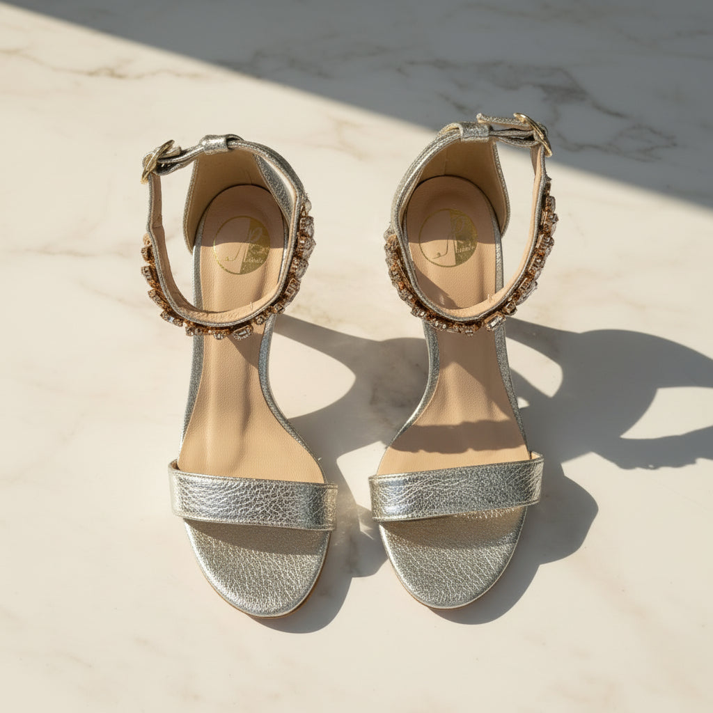 Pair of silver high-heeled sandals with decorative straps on a light background