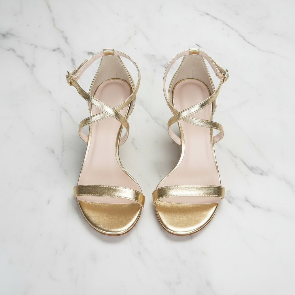 Gold high-heeled sandals on a marble surface