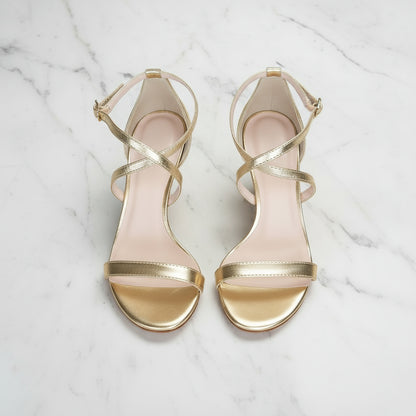 Gold high-heeled sandals on a marble surface