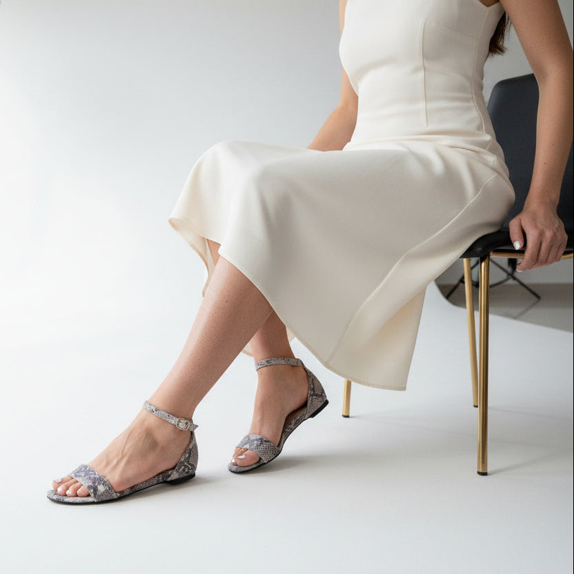 Person wearing silver high-heeled sandals in a minimalistic setting