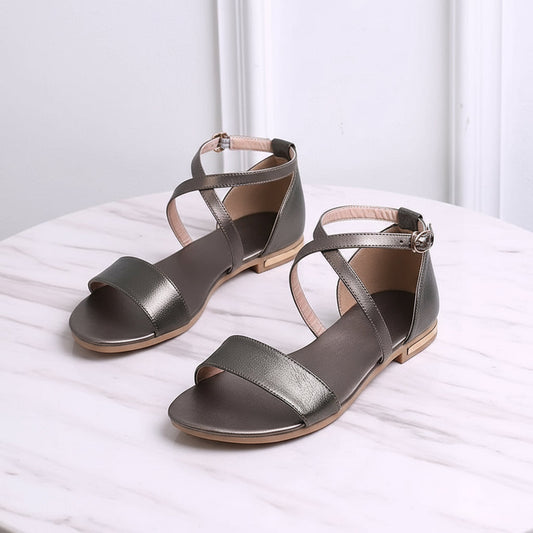 Pair of metallic green sandals on a white surface with a light gray background