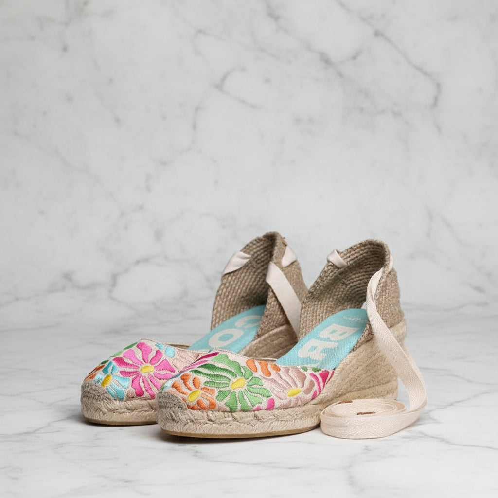 Pair of colorful floral espadrilles on a light gray background