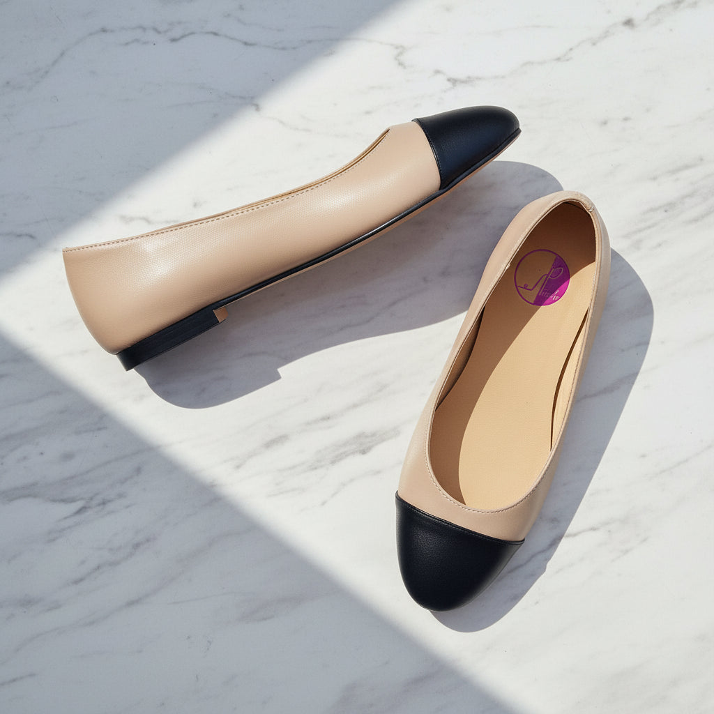Pair of beige and black flat shoes on a light marble background