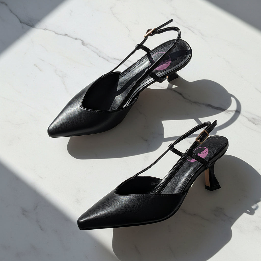 Black high-heeled slingback shoes with ankle straps on a white marble background