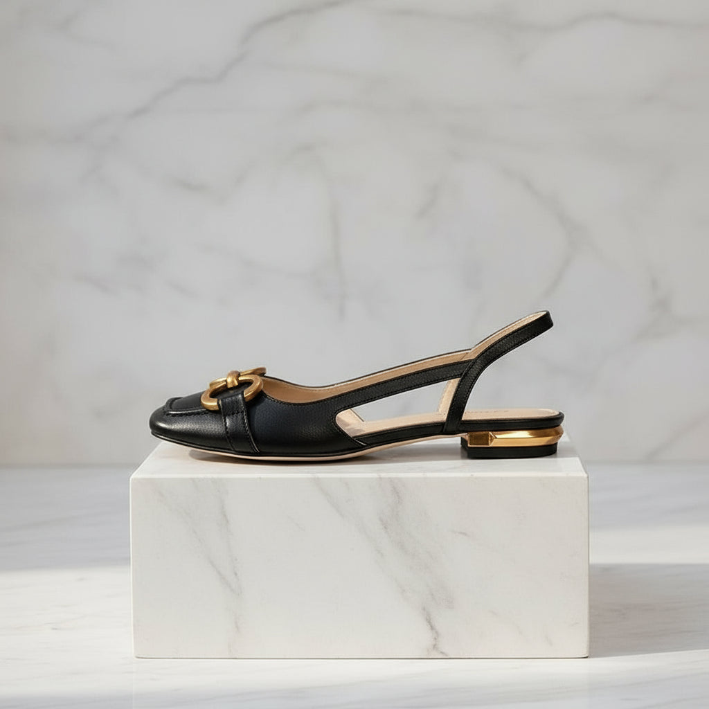 Black slingback sandals with gold accents on a light gray background