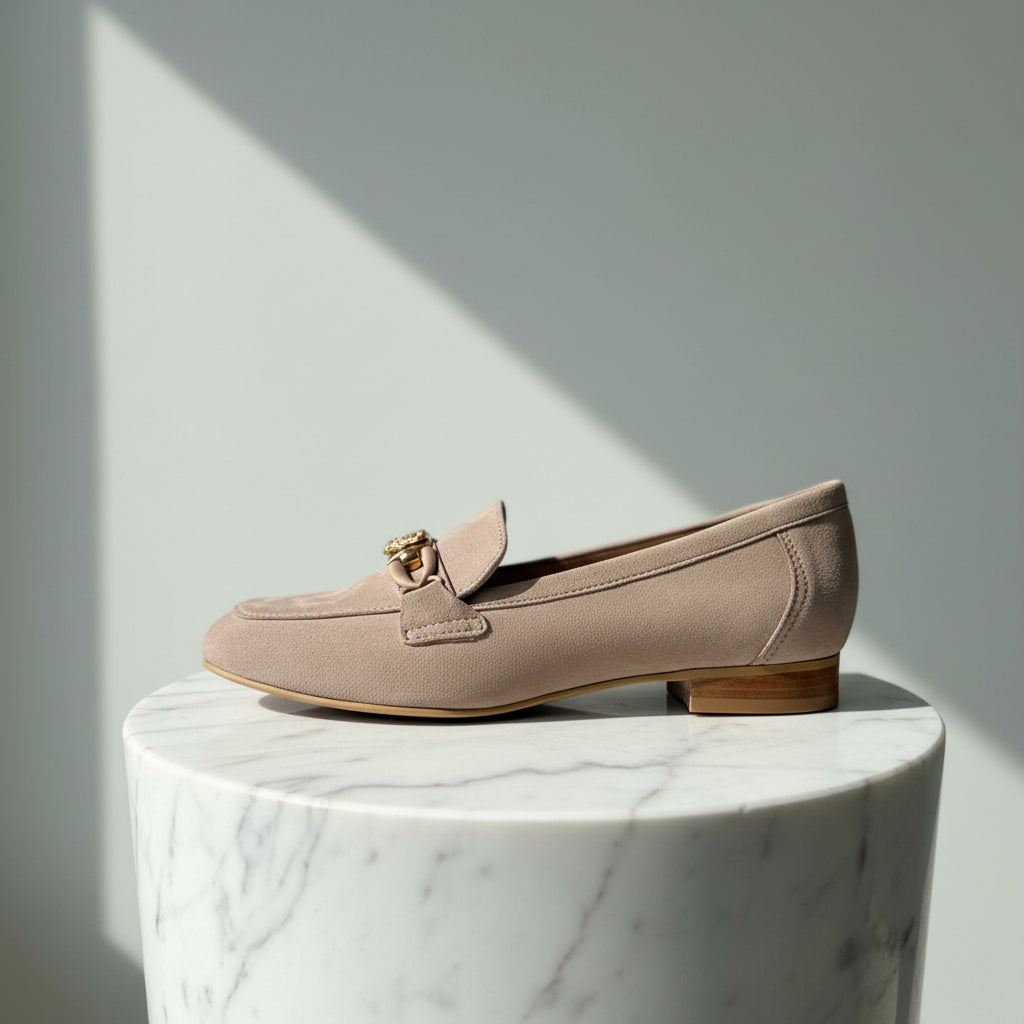 Beige loafers on a marble pedestal with a light gray background