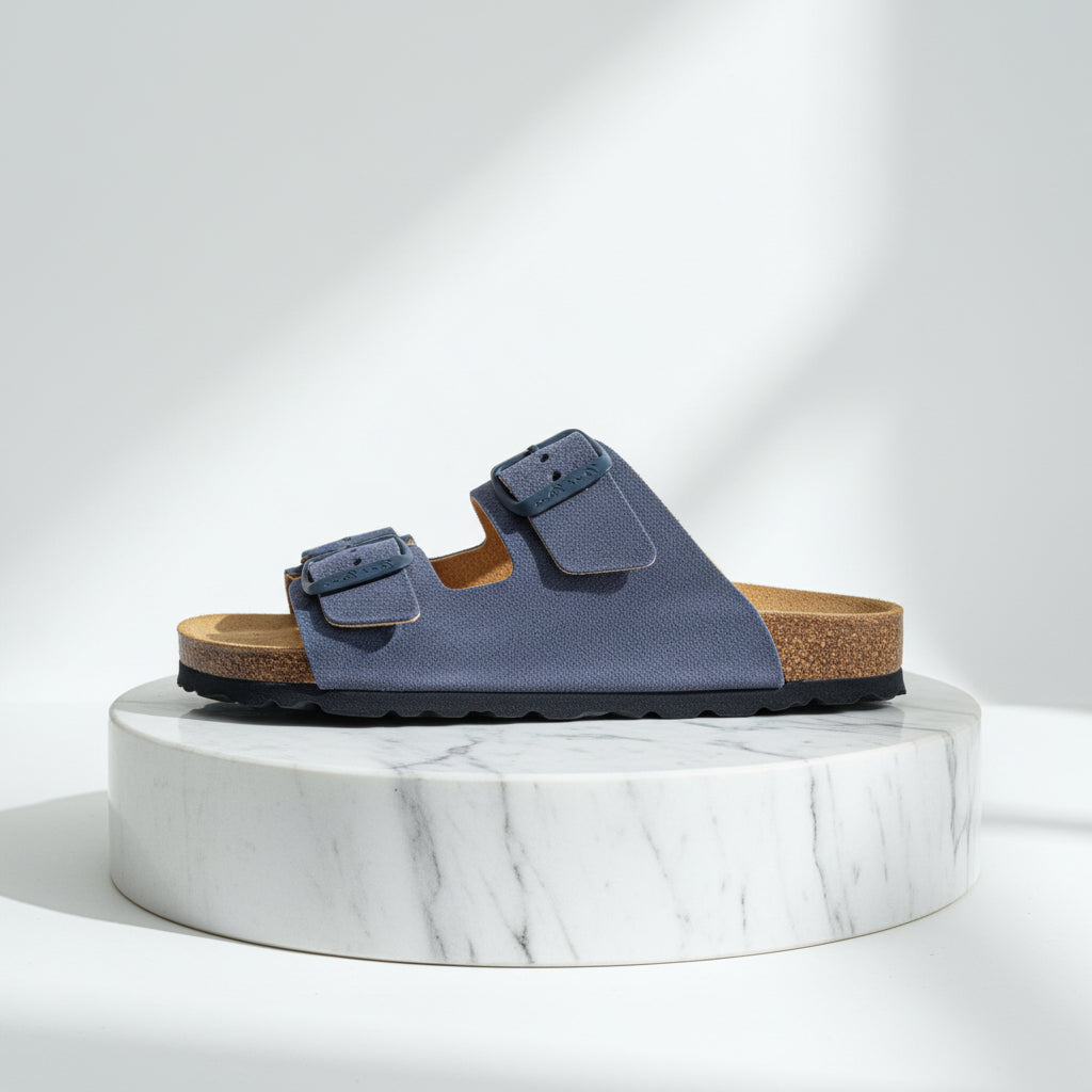 Blue sandal with cork sole on a marble platform against a white background