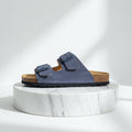 Blue sandal with cork sole on a marble platform against a white background