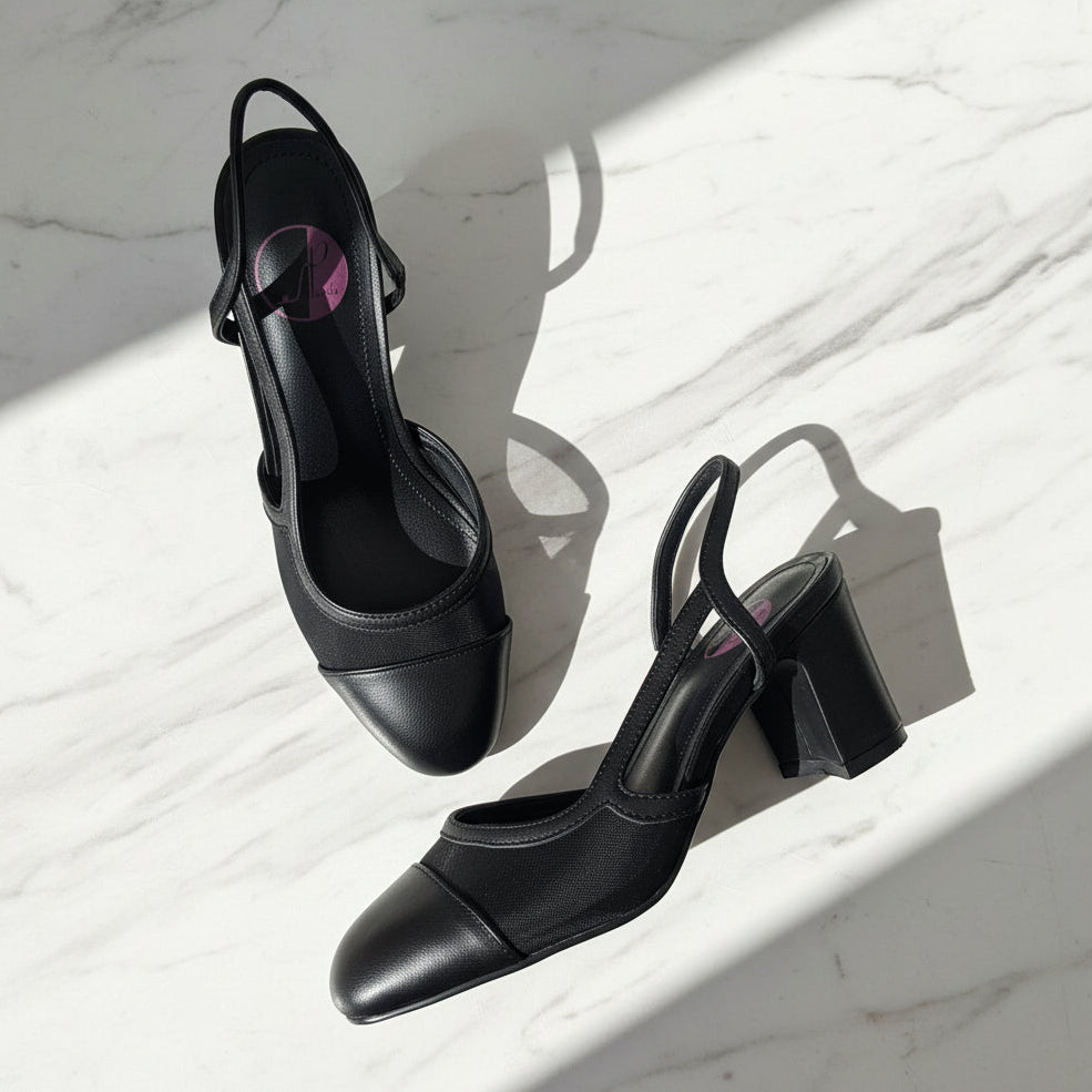 KAI black leather and mesh slingback block heel shoes flat lay on marble surface.
