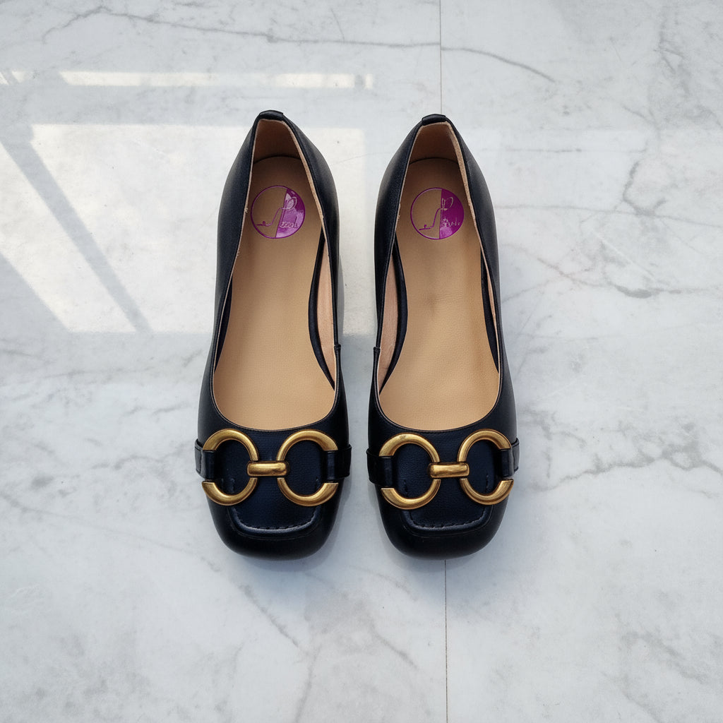 Black high-heeled shoes with gold accents on a light gray background