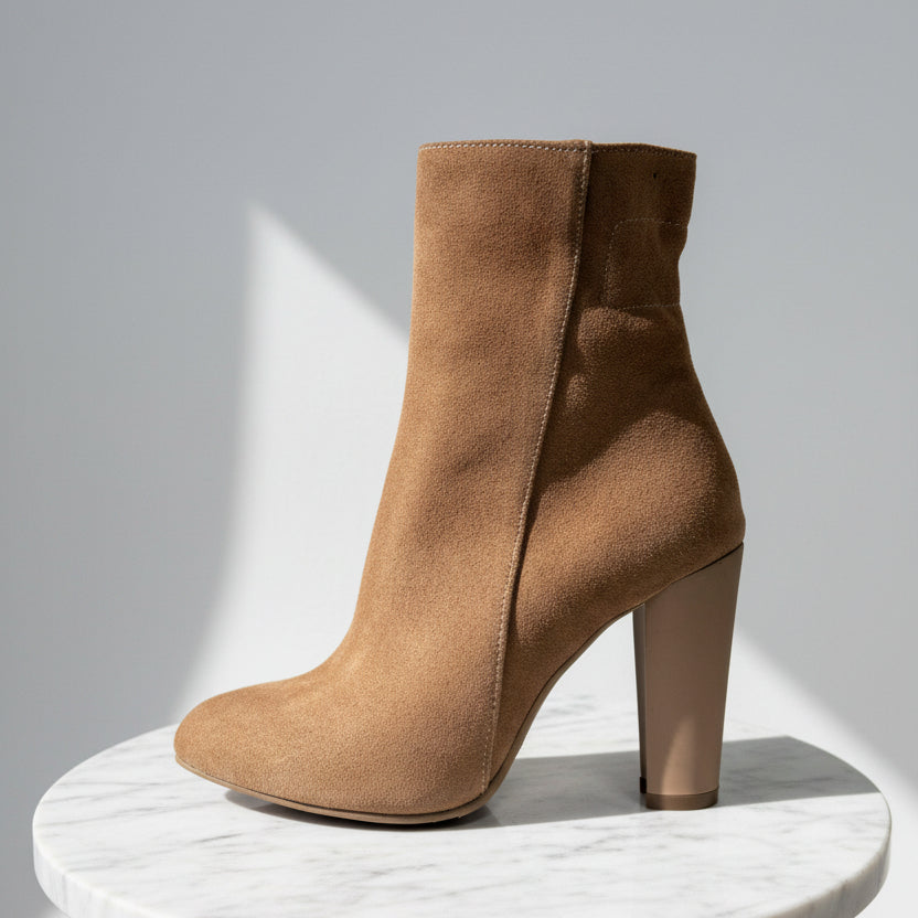 Brown ankle boot on a marble stand with a white background