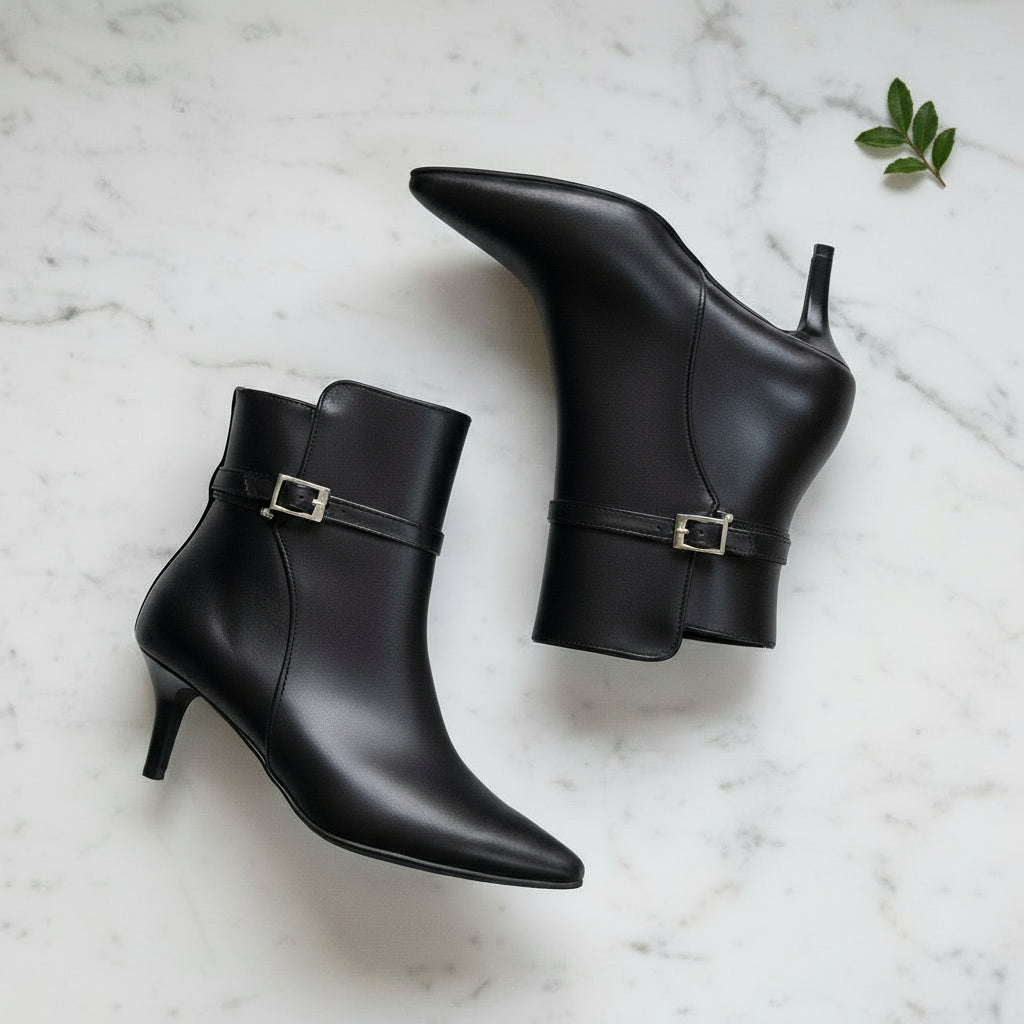 Black leather ankle boots with buckles on a marble surface