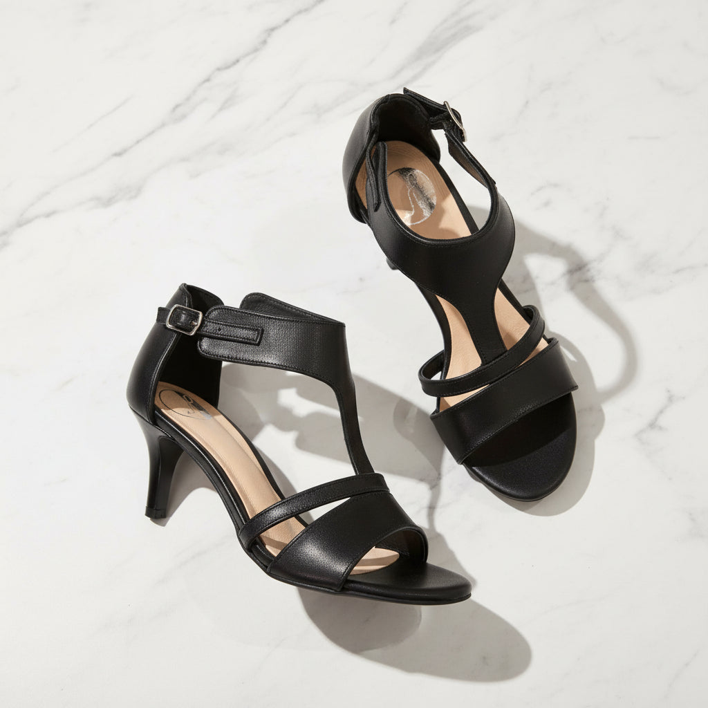 Black high-heeled sandals on a light gray background
