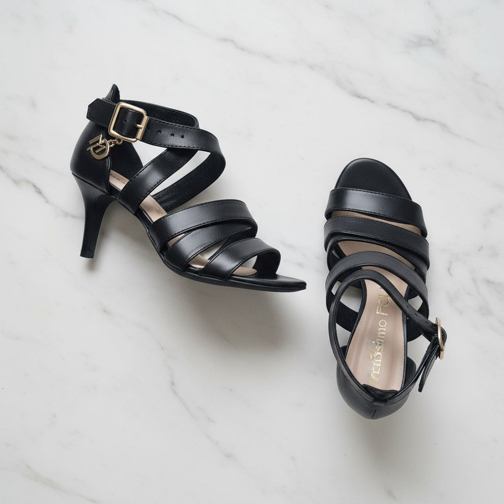 Black strappy high-heeled shoes on a white marble surface