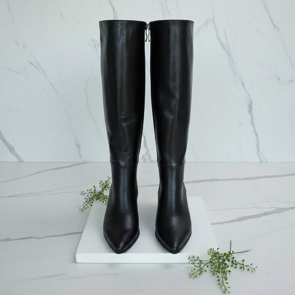 Black knee-high boots on a marble surface with a plant in the background