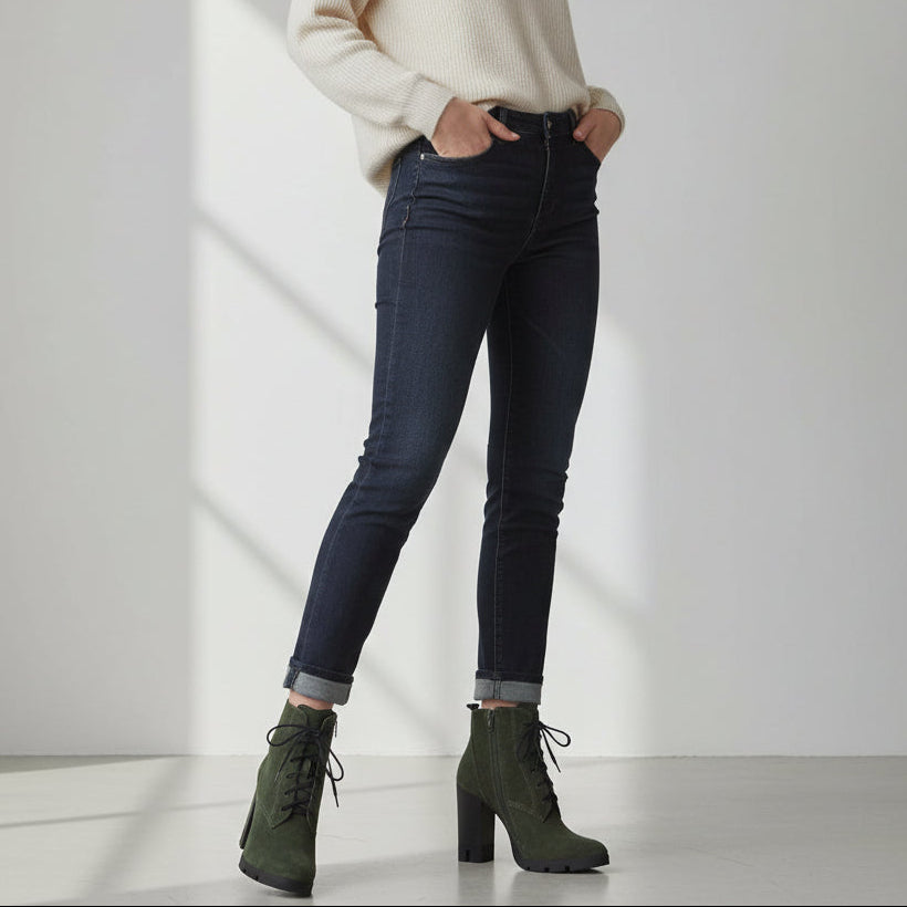 Person wearing dark jeans and green boots on a white background
