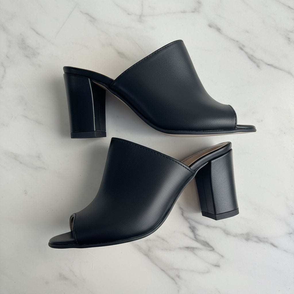 Black leather mules on a marble surface