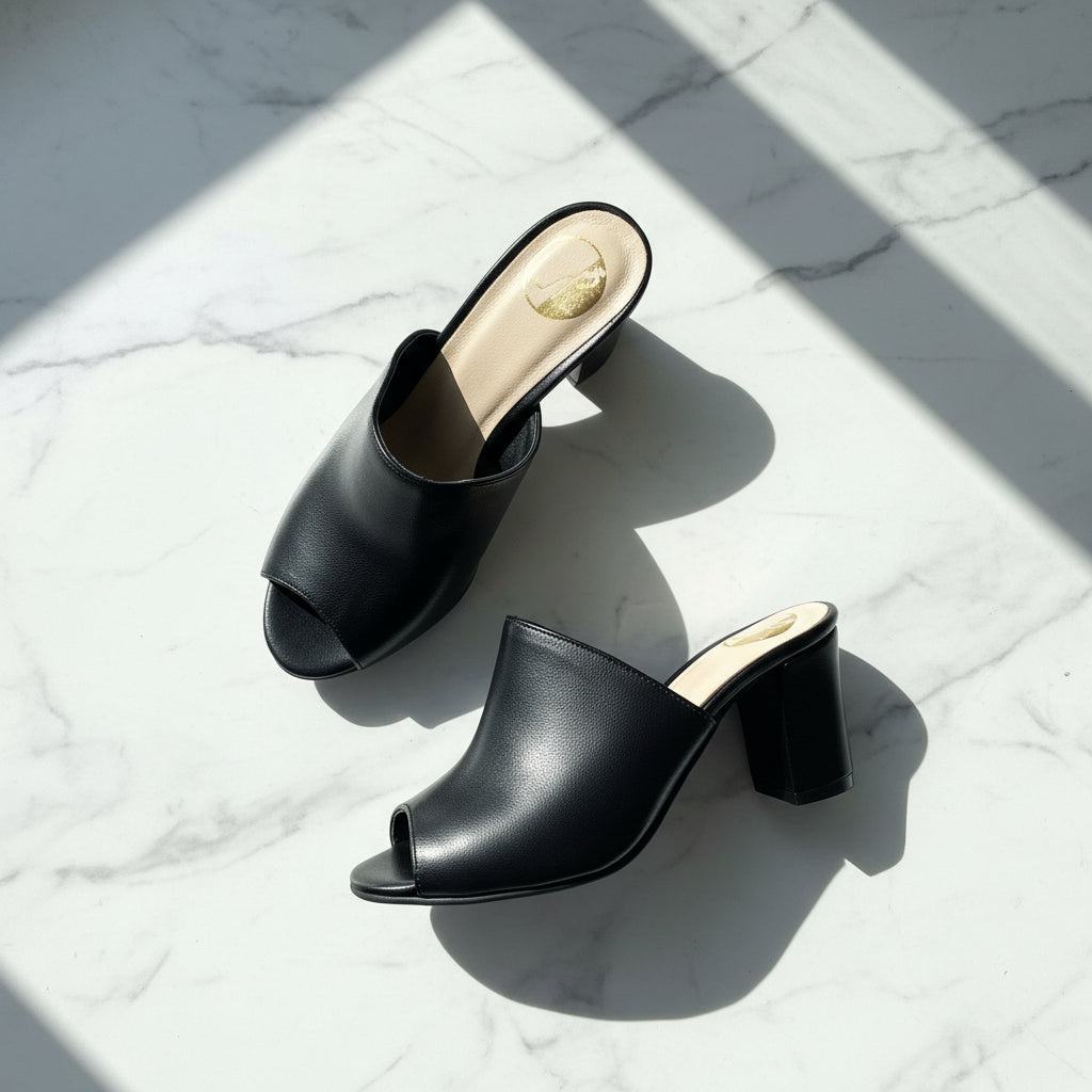 Black open-toe high-heeled shoes on a light marble surface
