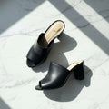 Black open-toe high-heeled shoes on a light marble surface