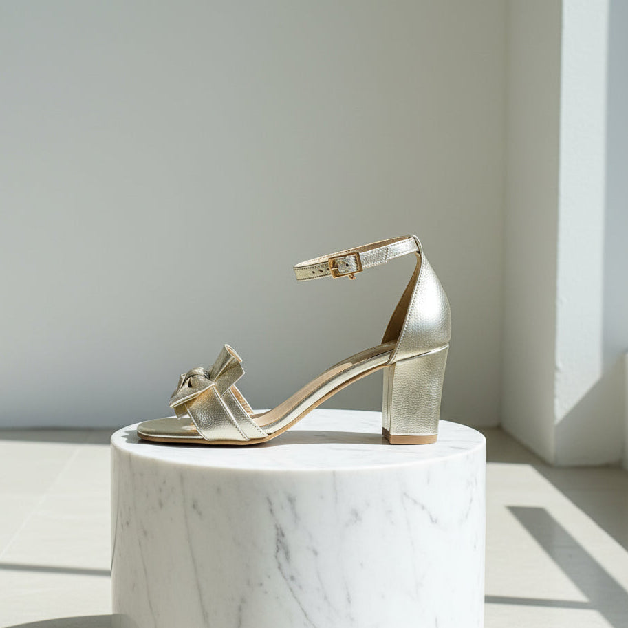 Gold high-heeled shoe on a white marble pedestal with a light gray background