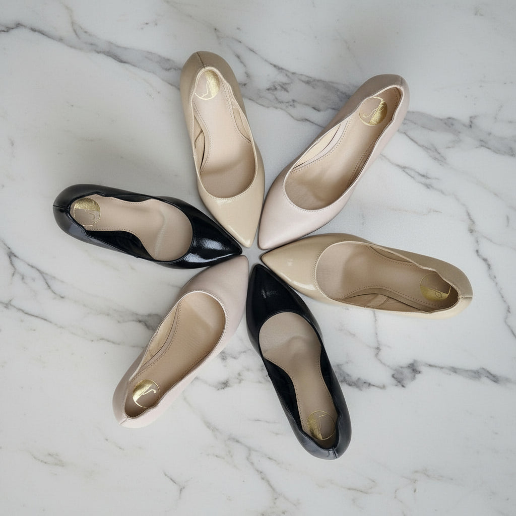 Top view of petite LUNA kitten heel court shoes in black patent and nude matte leather arranged in a circle on marble surface