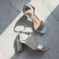 Silver high-heeled sandals on a light gray background