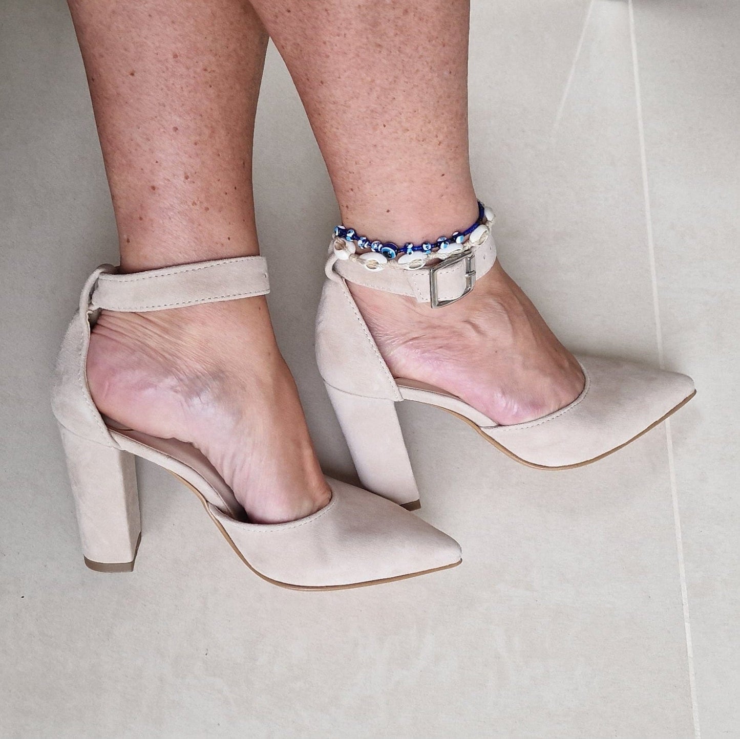 A woman wearing pointed toe court shoes in nude suede leather