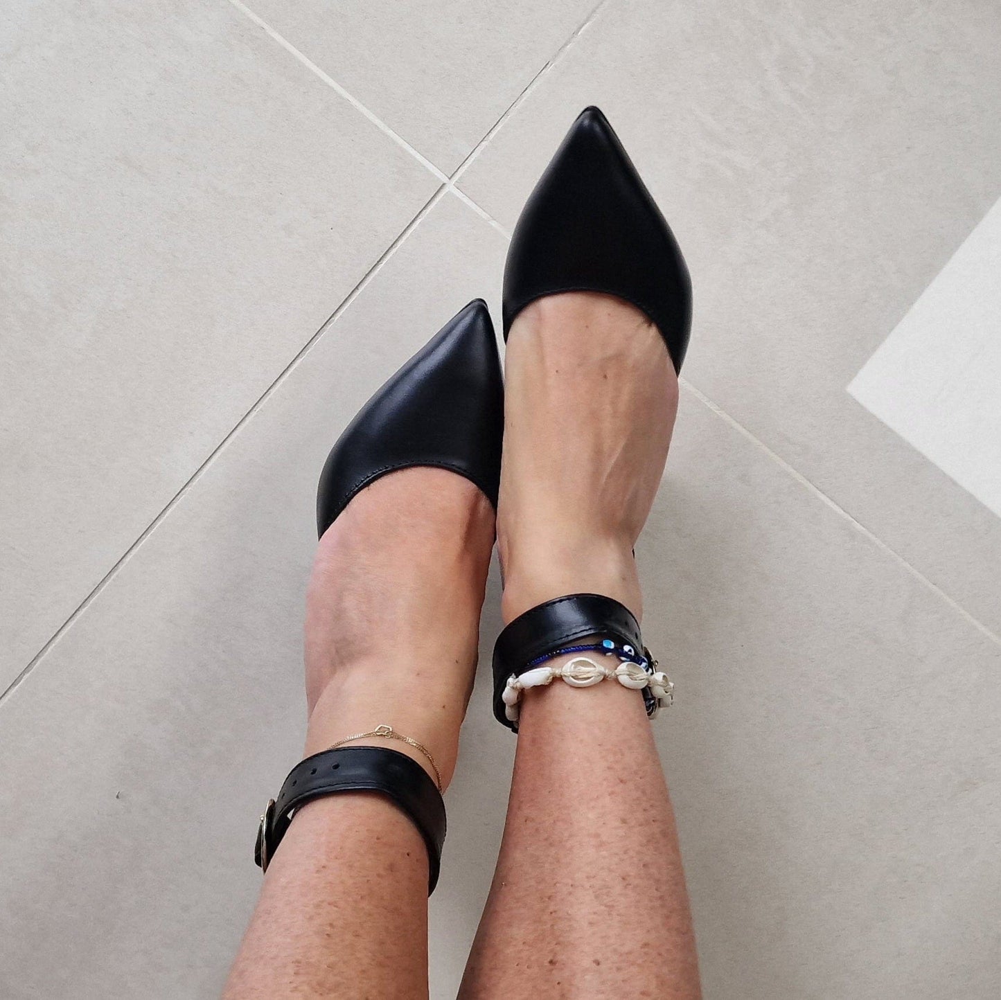 A woman wearing pointed toe black leather heels
