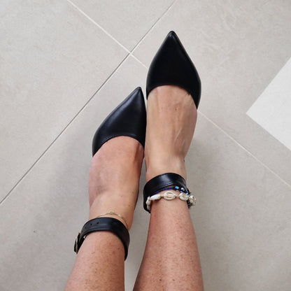 A woman wearing pointed toe black leather heels