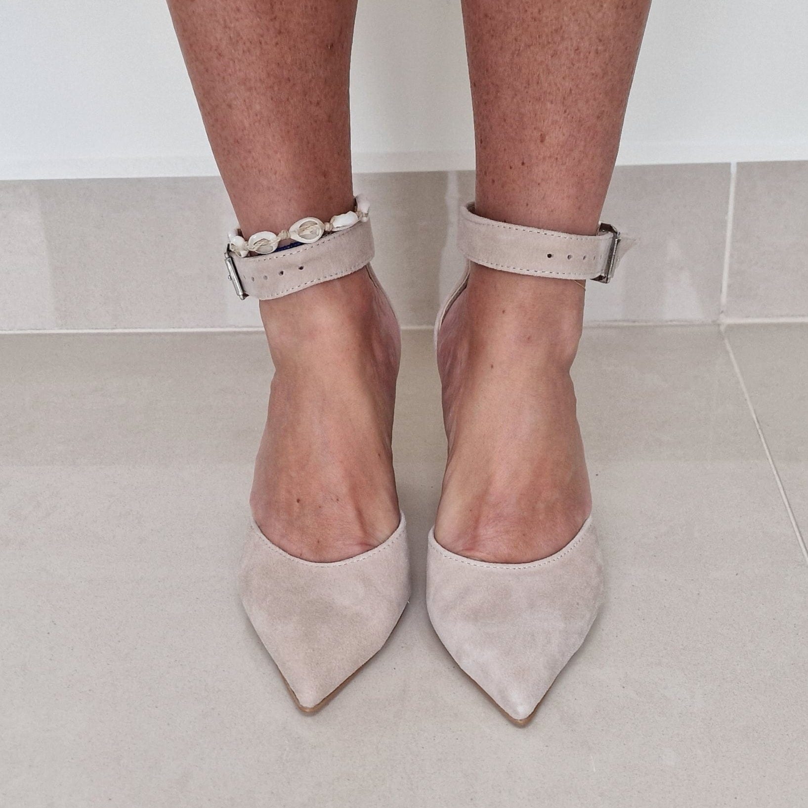 A woman wearing pointed toe ankle strap court heels