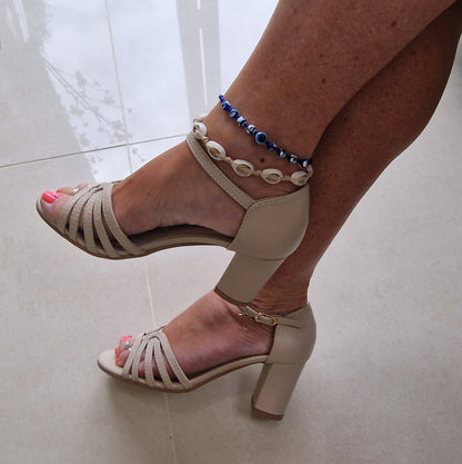 A woman wearing nude leather strap sandals set on a block kitten heel