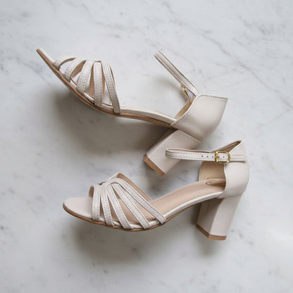 Pair of beige high-heeled sandals on a marble surface