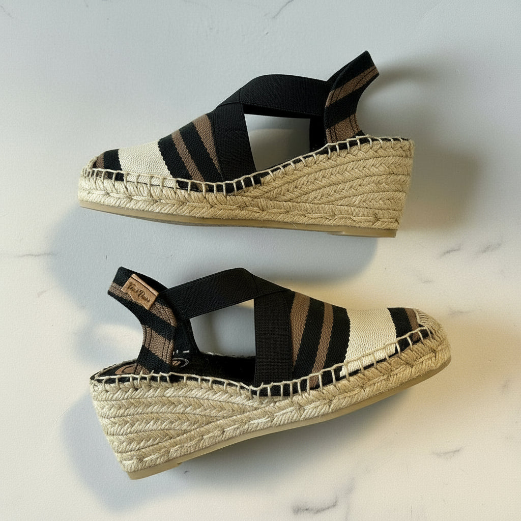 Pair of black and beige striped wedge sandals on a light background
