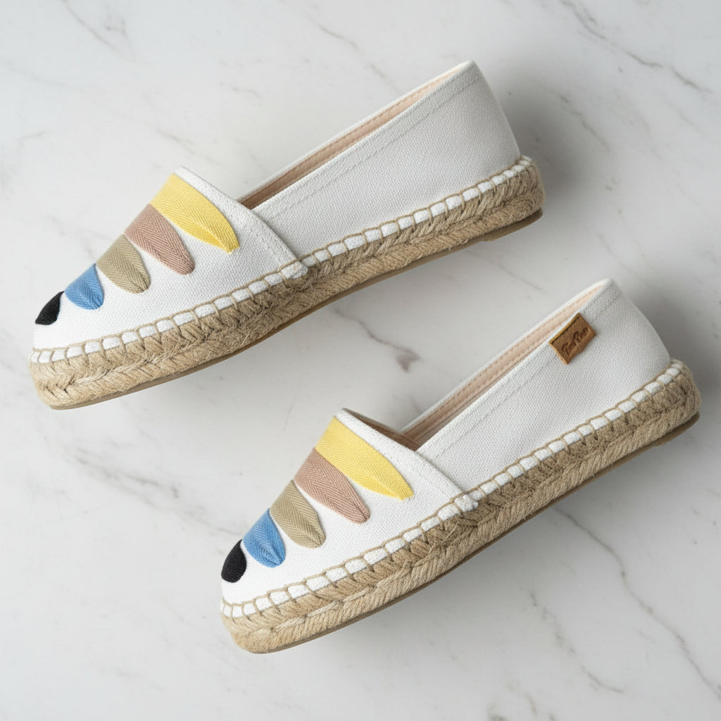 Pair of white espadrilles with colorful sole on a light gray background