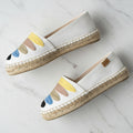 Pair of white espadrilles with colorful sole on a light gray background