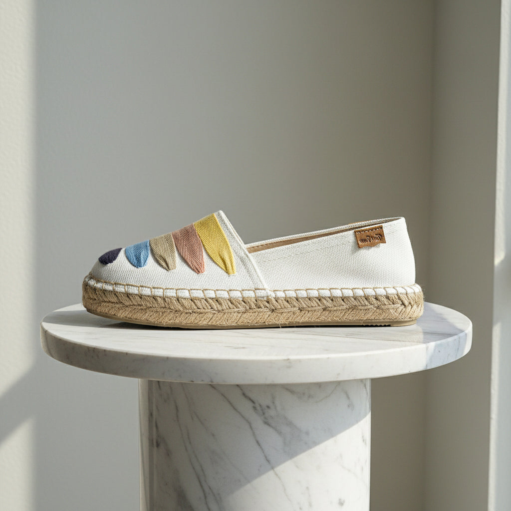 White espadrille shoe with colorful accents on a marble surface
