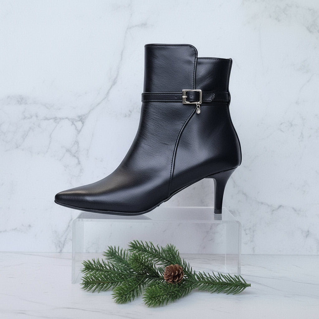 Black leather ankle boot with a strap on a marble background