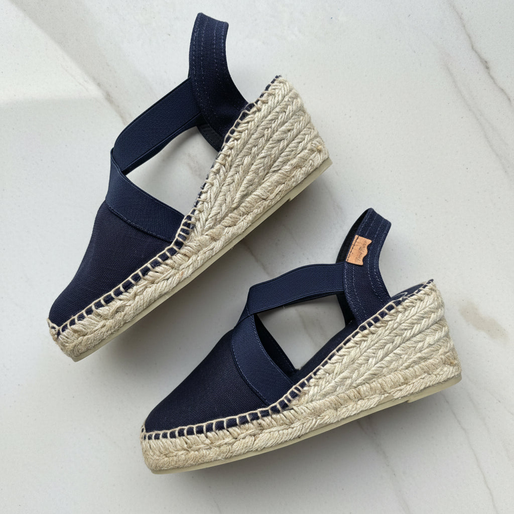 Navy blue espadrilles with woven jute sole on a light background