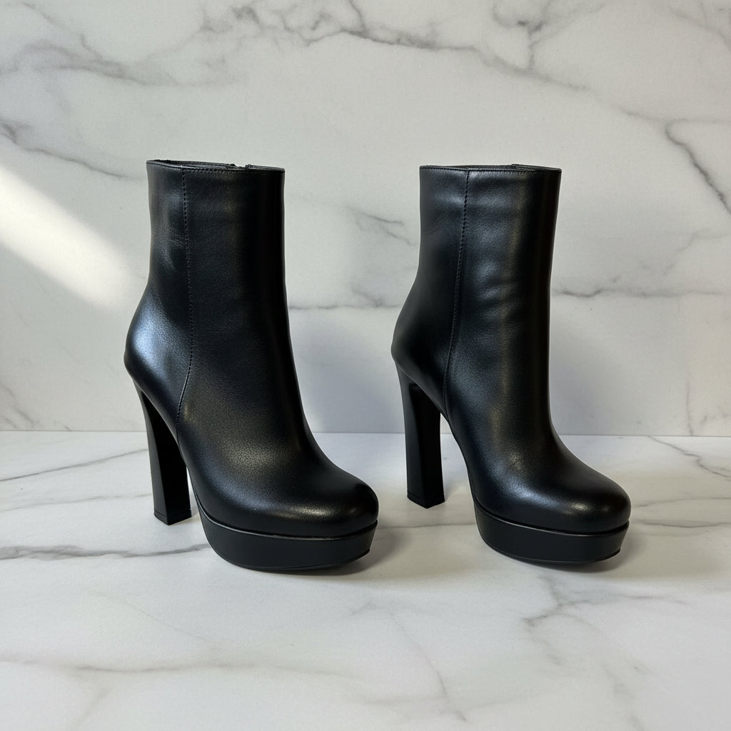 Black high-heeled platform boots on a marble surface