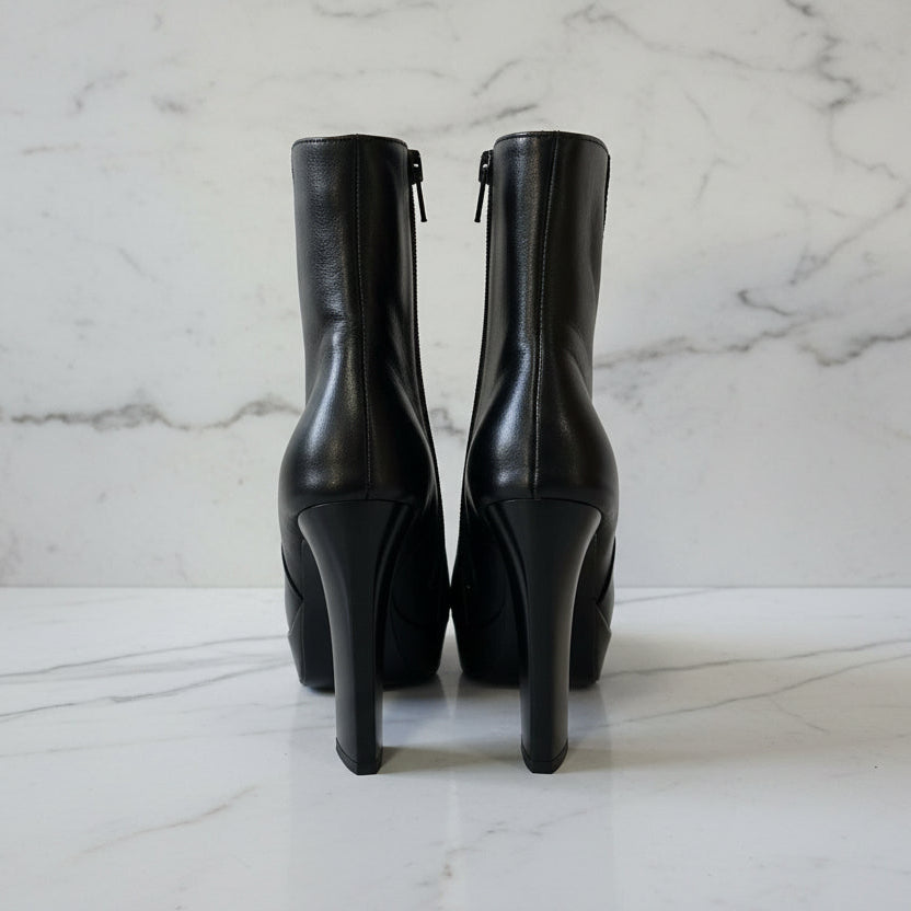 Pair of black high-heeled boots on a marble surface