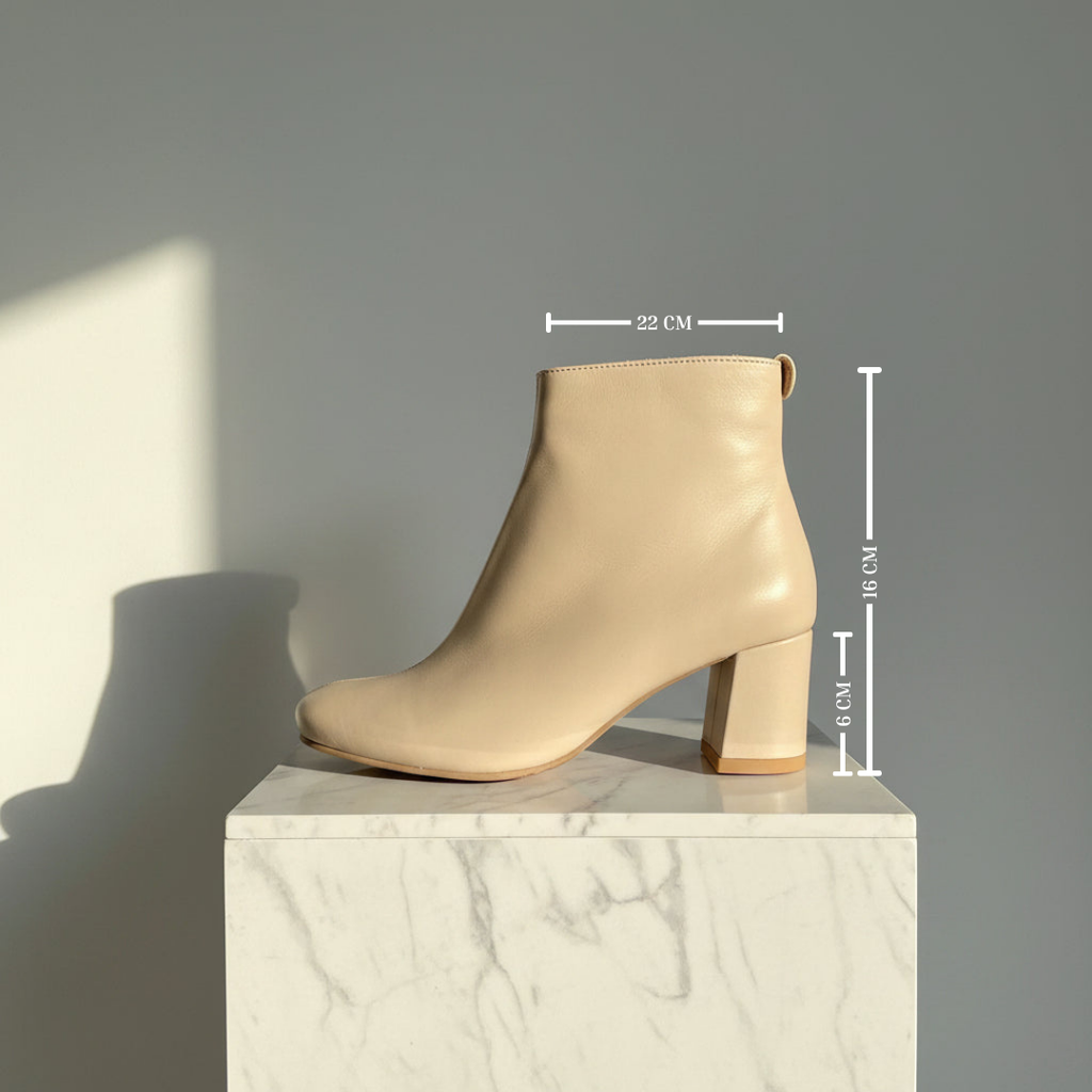 A beige ankle boot with a block heel and rounded toe, displayed on a white marble pedestal against a gray wall. White dimension lines overlay the boot showing measurements of 22 cm, 15 cm, and 9 cm.