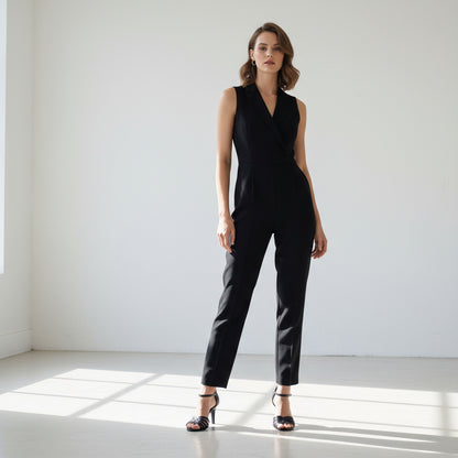 Woman wearing a black jumpsuit standing in a well-lit room with sunlight casting shadows on the floor.