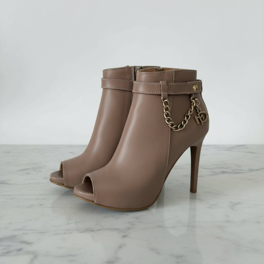 Brown high-heeled boots with gold chain and decorative buckle on a light gray background