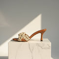 Brown leather and natural jute petite mule sandal elevated on a marble pedestal.