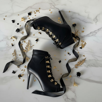 Flatlay of ORIA black lace-up boots with gold hoop eyelets among black and gold accents.